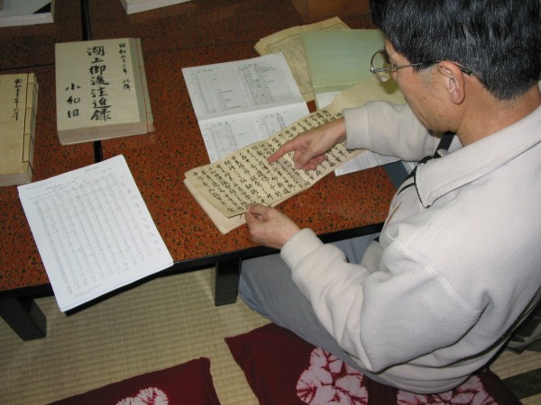 photo of a man pointing to records in a character-based script