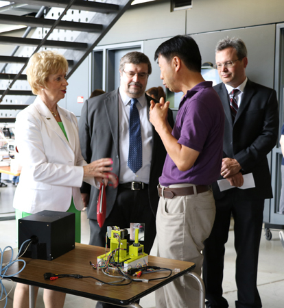 photo of MP Judy Sgro touring various demonstrations of equipment and research. Speaking to Sgro is Bob Hou, senior research assistant in the Centre for Vision Research. Looking on are York VPRI Robert Haché and VISTA Scientific Director Doug Crawford.