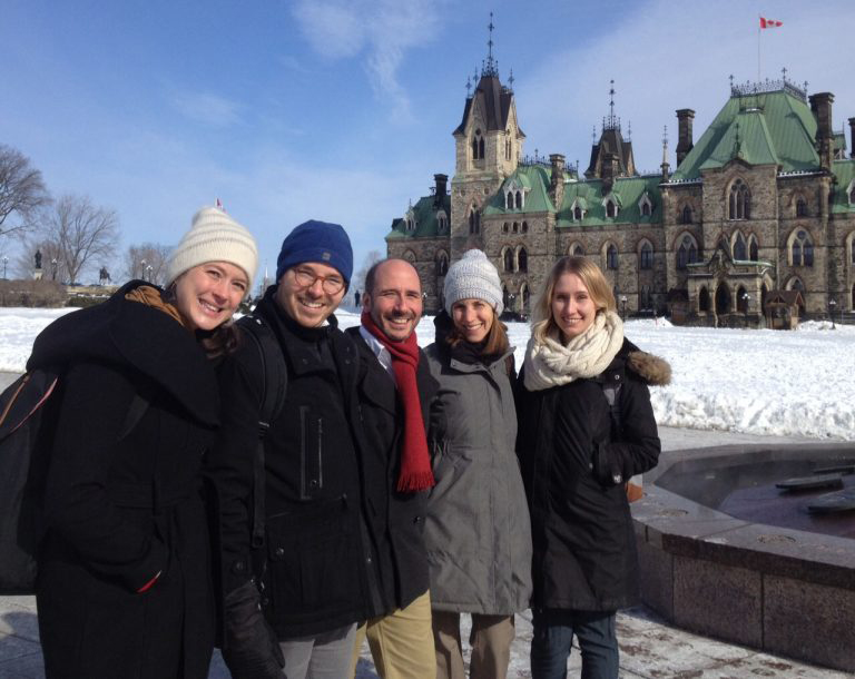photo of five people on Parliament Hill with the West Block in the background
