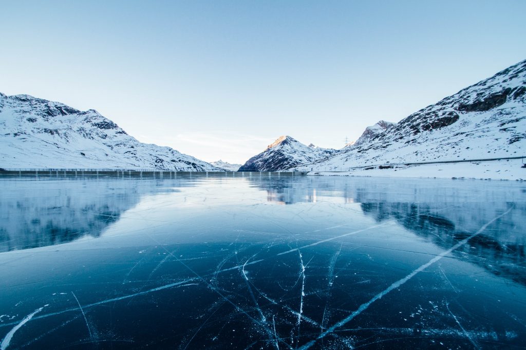 photo of a frozen lake with mountains in the background
