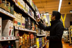 photo of Kam Phung examining a package of coffee in front of supermarket shelves