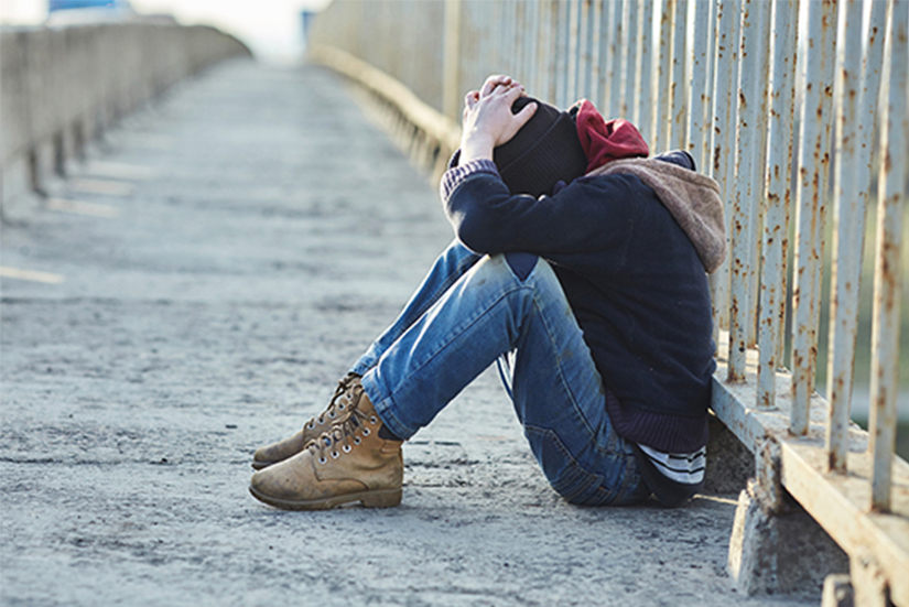 photo of a young homeless boy sleeping on a bridge