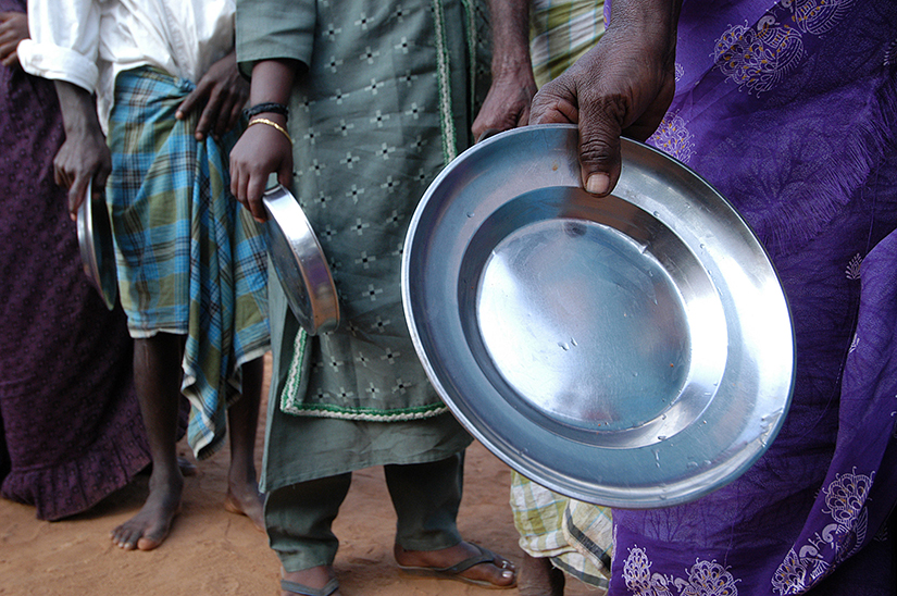 cropped photo of people lining up for food in a refugee camp